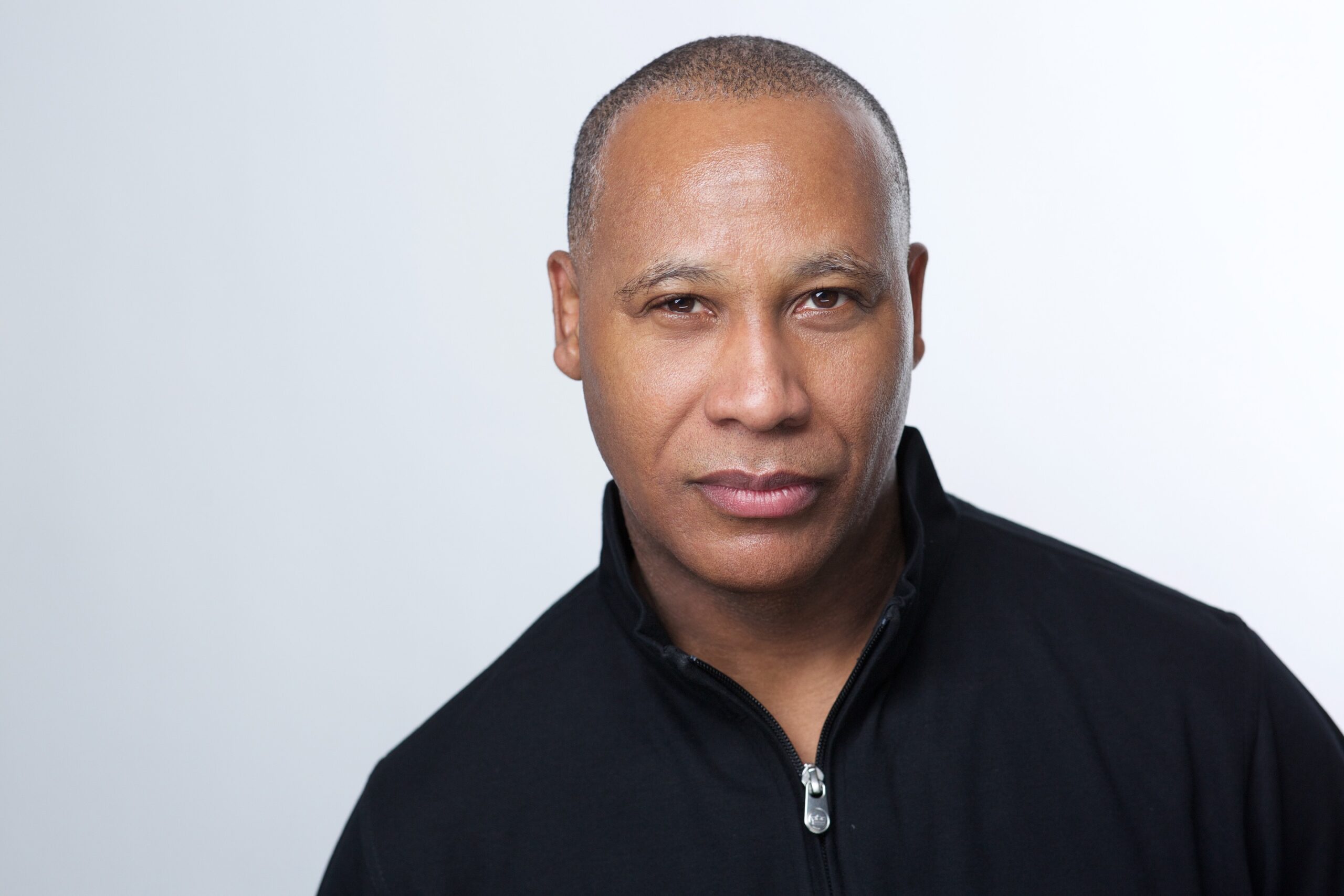 Professional headshot NYC — man in black zip-up jacket on white background